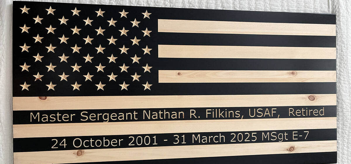 Wooden American flag with engraved text on a textured wall background